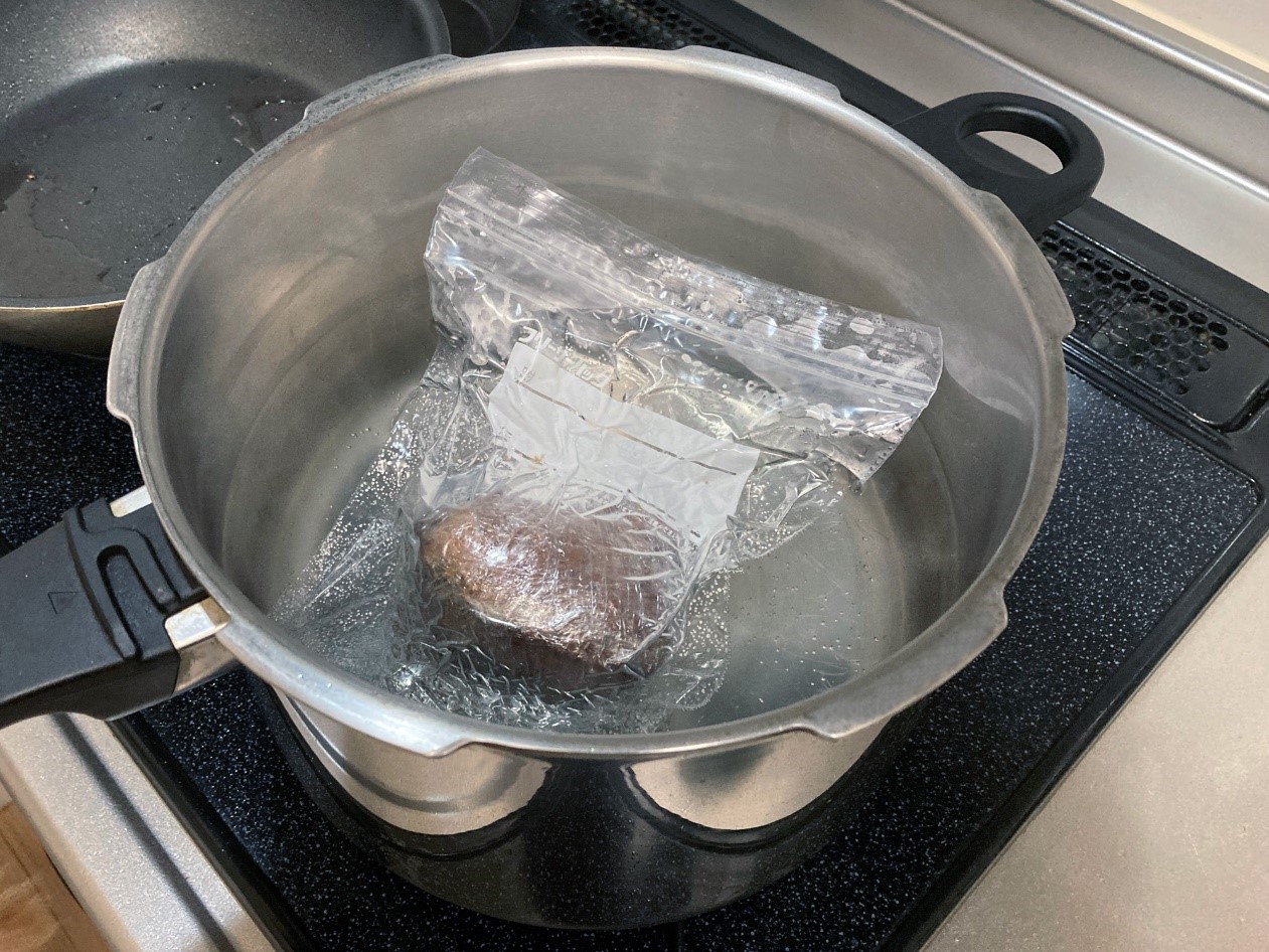 湯を沸かしたなべに塊の牛モモ肉を入れて湯煎で作るローストビーフ